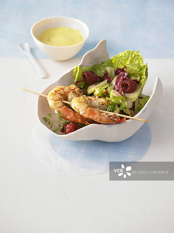 色彩鲜艳的覆盆子沙拉配鲜虾串和香槟蘸酱图片素材