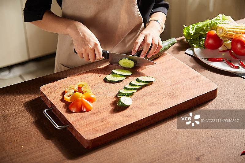 一个人在厨房用刀在砧板上切蔬菜图片素材