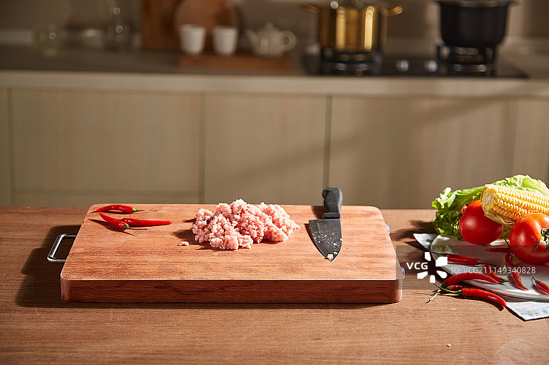 一个人在厨房用砧板切肉图片素材