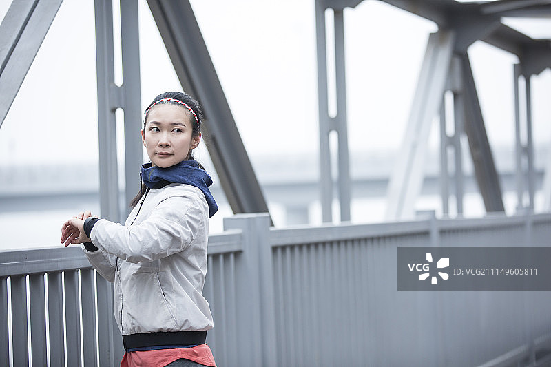 青年女子在跨海大桥上查看智能手表图片素材