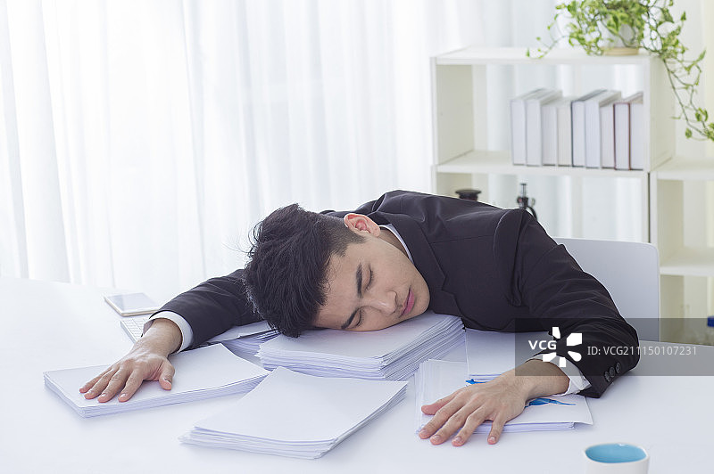 一位办公男性趴在桌上过劳死图片素材