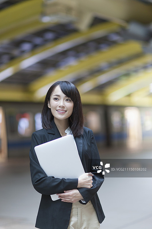 一位办公女性拿着笔记本电脑图片素材