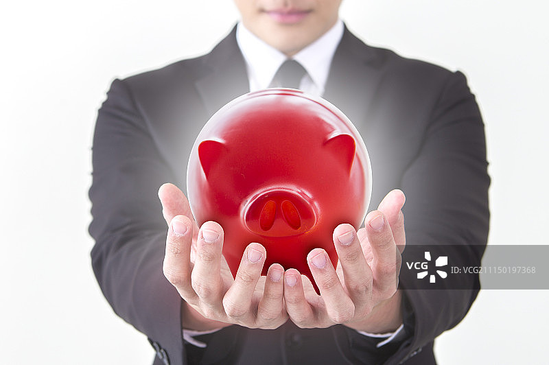 一位办公男性捧着红色小猪扑满图片素材