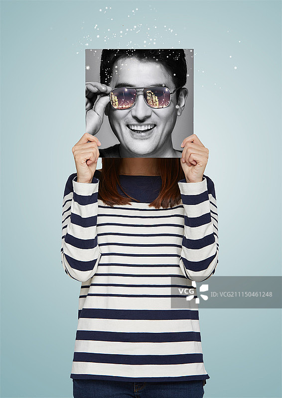 手拿人脸照片的女人图片素材