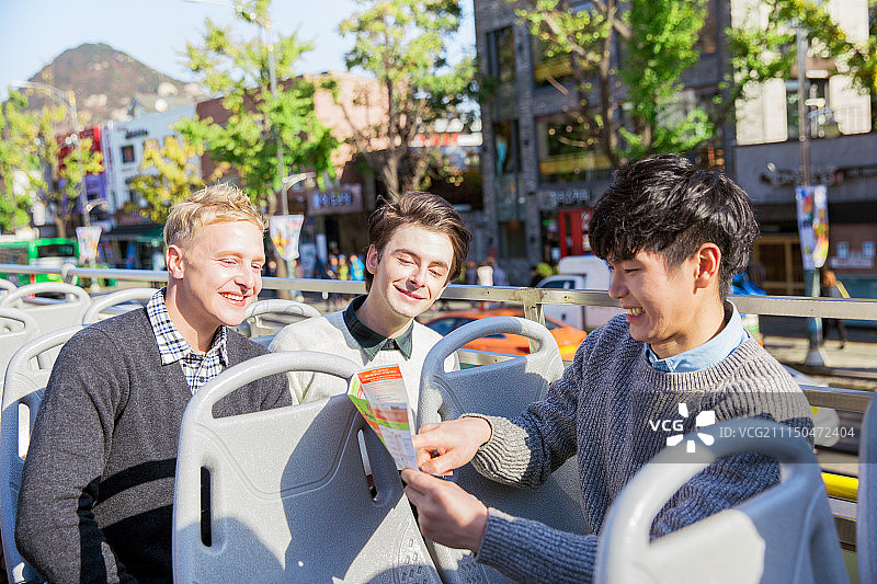 外国人，白人，在首尔乘坐旅游巴士，微笑，满意，城市街道，看地图和指南图片素材