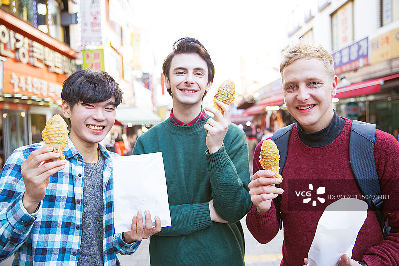 在南大门市场观光，品尝街头美食的韩国籍男性游客图片素材