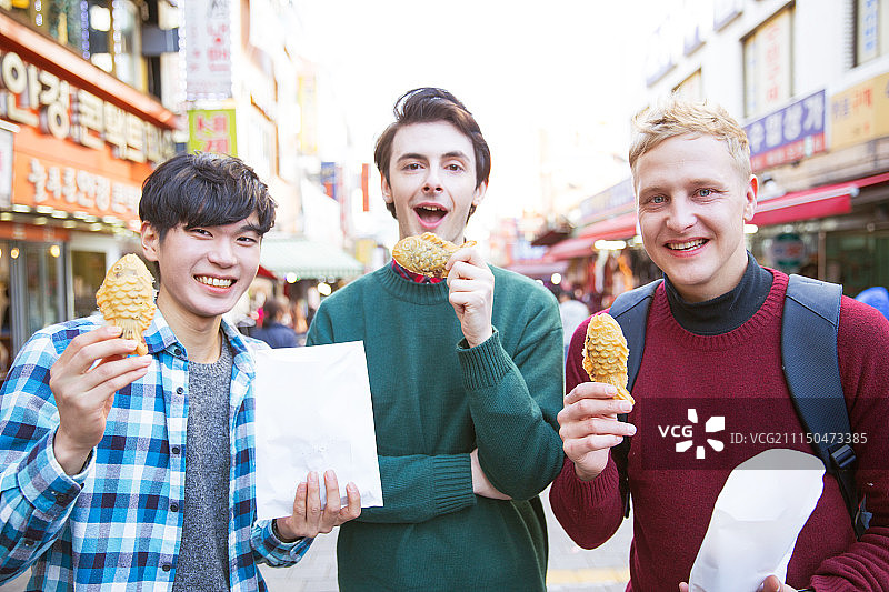 在南大门市场观光，品尝街头美食的韩国籍男性游客图片素材