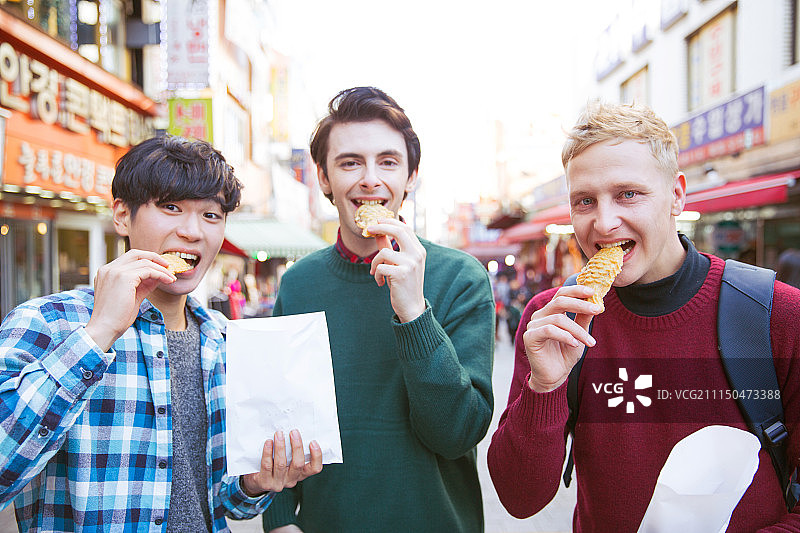 在南大门市场观光，品尝街头美食的韩国籍男性游客图片素材