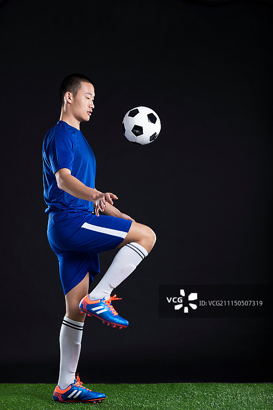 一名年轻足球运动员在草地上踢足球图片素材