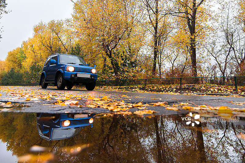 雨天秋季道路上的蓝色铃木吉姆尼图片素材