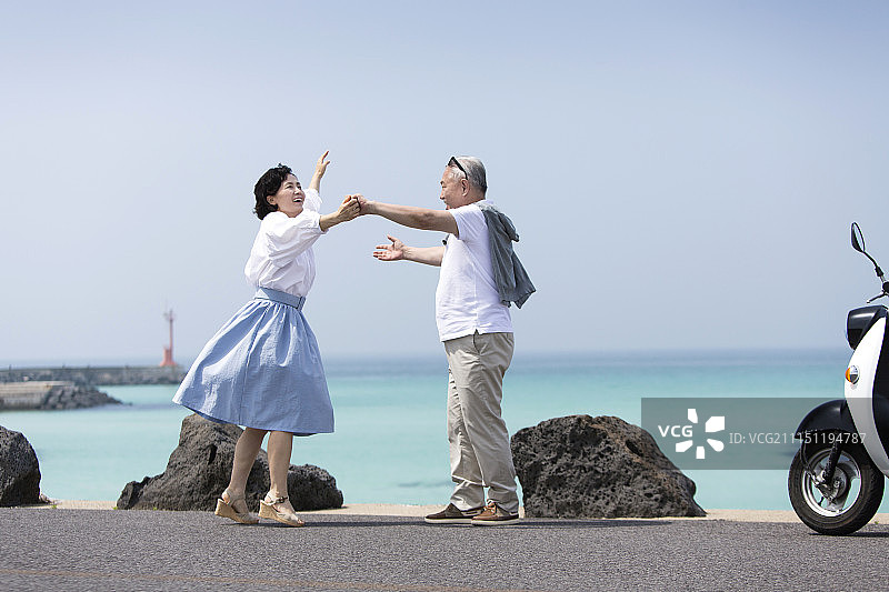 老年夫妇在沿海公路跳舞摄影图片素材
