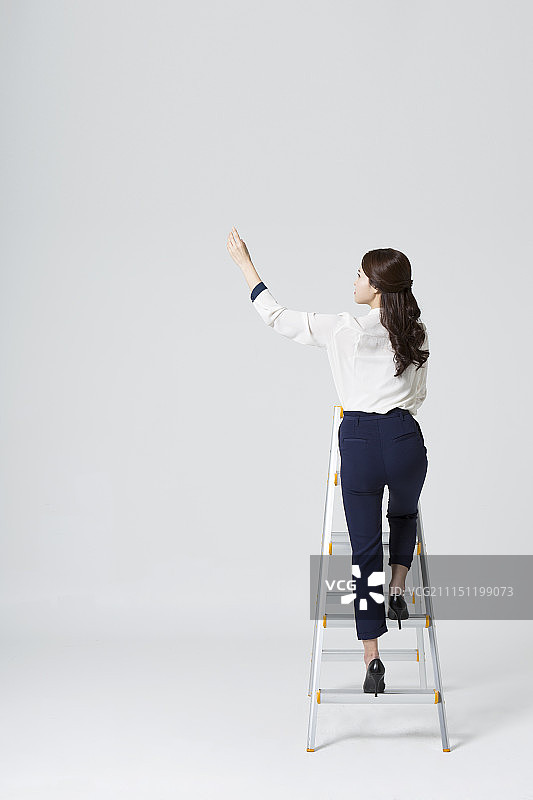 女商人站在梯子上伸手图片素材