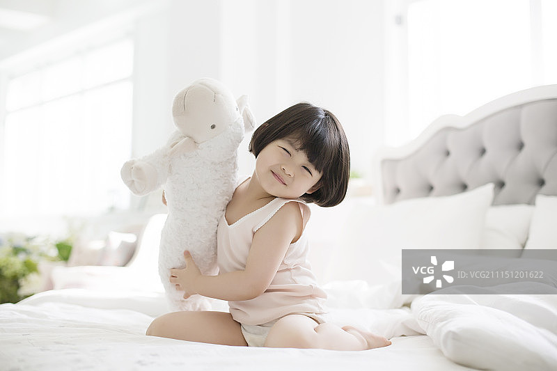 在床上玩洋娃娃的小女孩图片素材