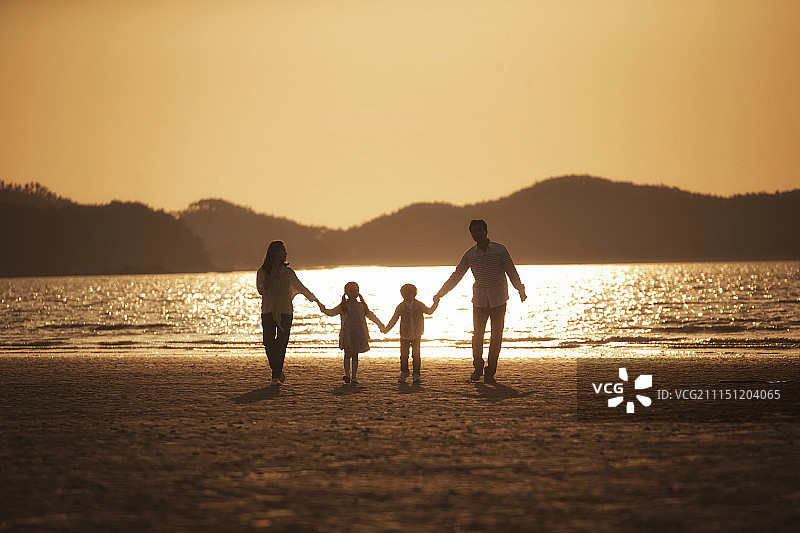 一家人在日落时分的沙滩上玩耍图片素材
