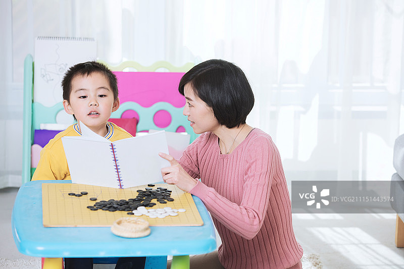 妈妈陪着儿子在客厅里一起看书学习图片素材