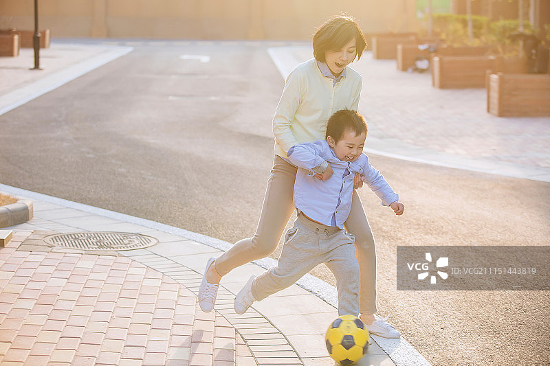 母亲陪孩子在户外踢足球图片素材