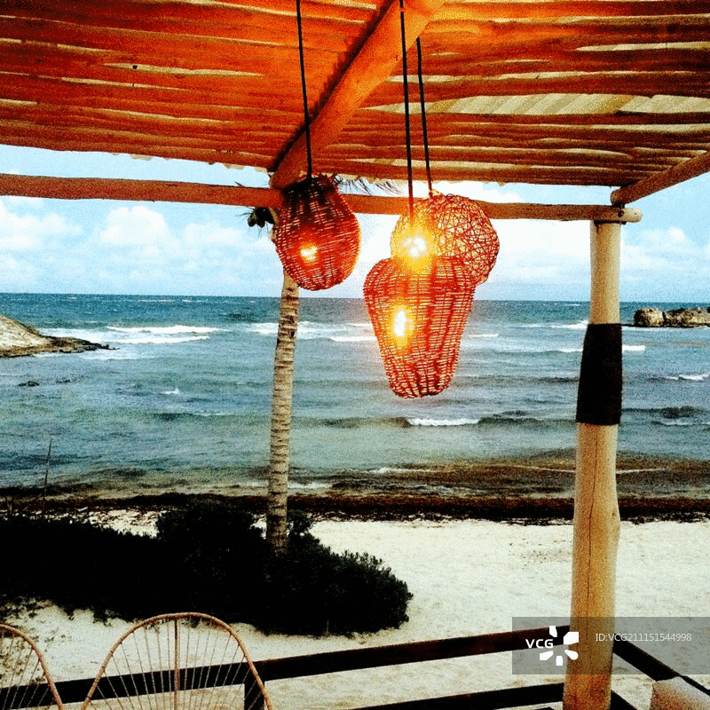 墨西哥图卢姆海滩凉棚上悬挂的纸灯笼与滚滚海浪背景图片素材