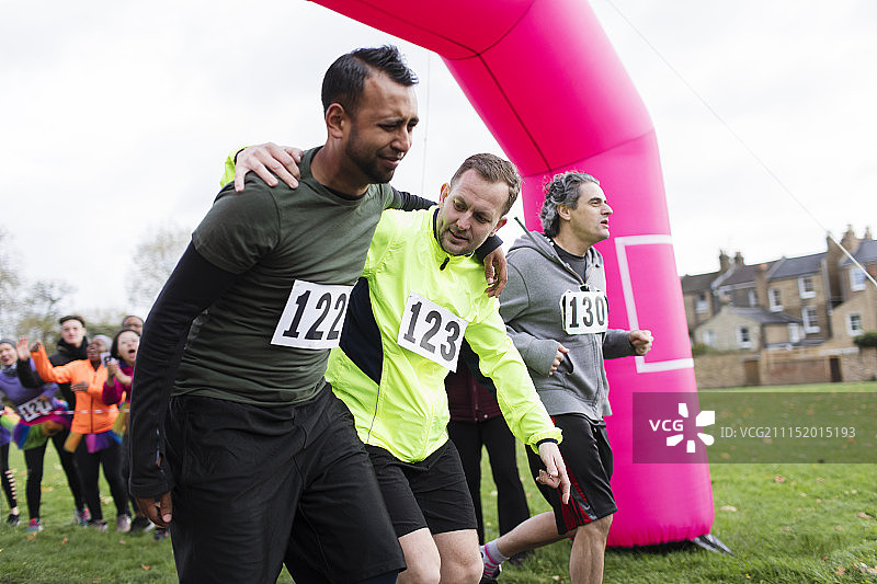 男子帮助受伤的赛跑者冲过慈善跑终点线图片素材