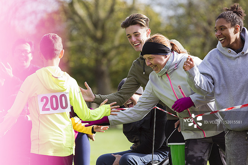 公园慈善跑步活动中，观众与跑步者击掌图片素材