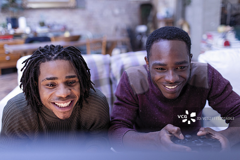 微笑的兄弟在玩电子游戏图片素材