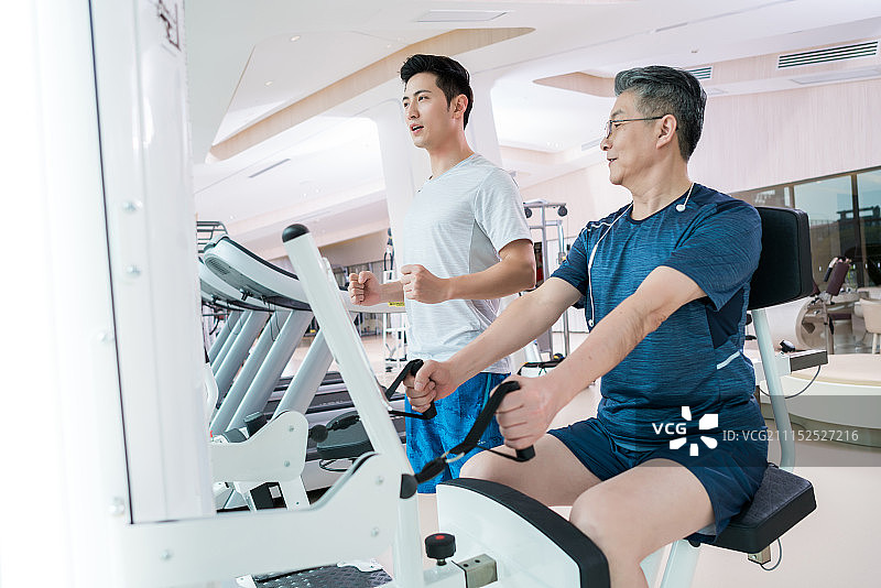 老年男子在私教指导下在健身房健身图片素材