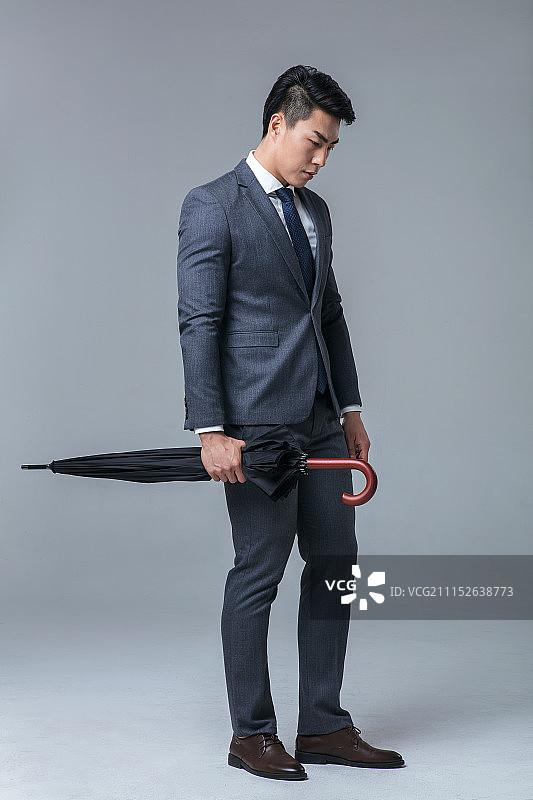 拿着黑色雨伞的年轻男士图片素材