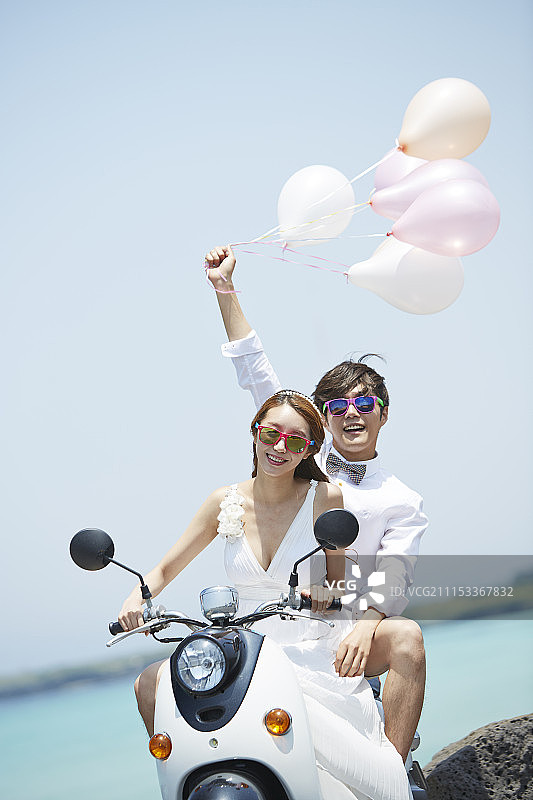 情侣戴墨镜骑摩托在沿海公路手持气球摄影图片素材