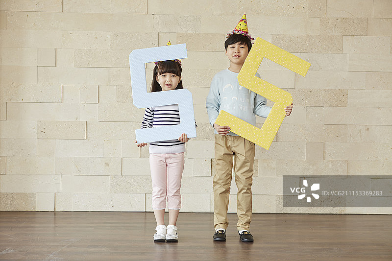 戴着派对帽的小男孩和小女孩拿着数字55的照片图片素材