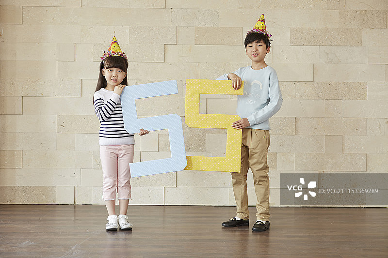 戴着派对帽的小男孩和小女孩拿着数字55的照片图片素材