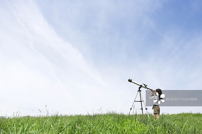 在草地上用望远镜观看的学龄前女孩摄影图片素材