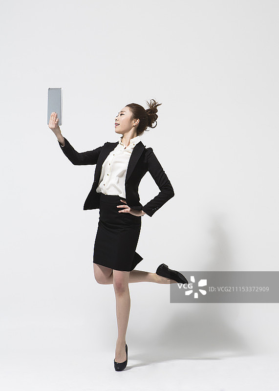 穿西装手持平板电脑在白色背景上跳舞的女人照片图片素材