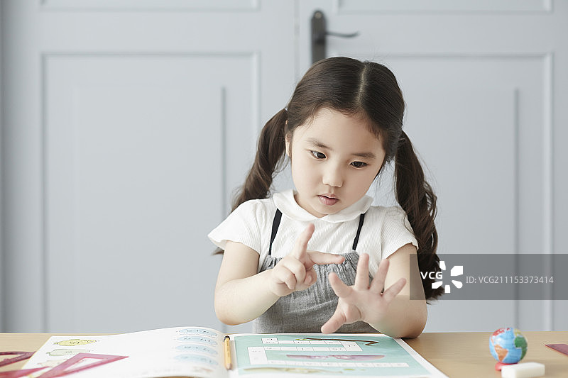 坐着学习数数的小女孩摄影图片素材