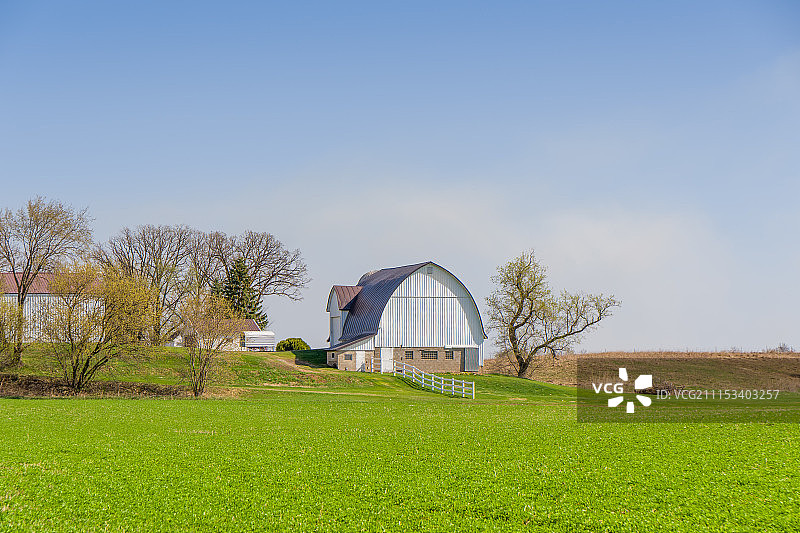 春天里的白色谷仓和绿色田野图片素材
