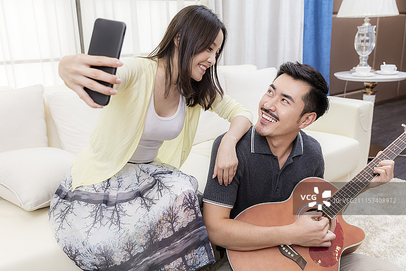 年轻的夫妻在客厅弹吉他图片素材