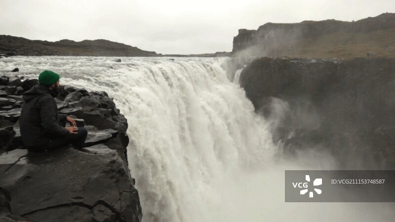 男人坐在瀑布边图片素材