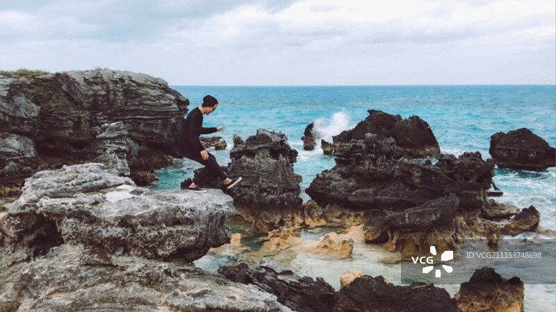 男子在海滩的大岩石上跑步图片素材