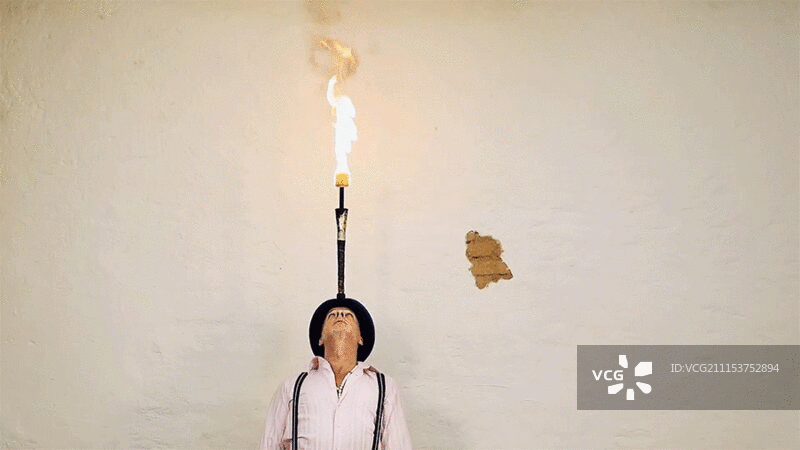 男人头顶平衡燃烧的棍子图片素材
