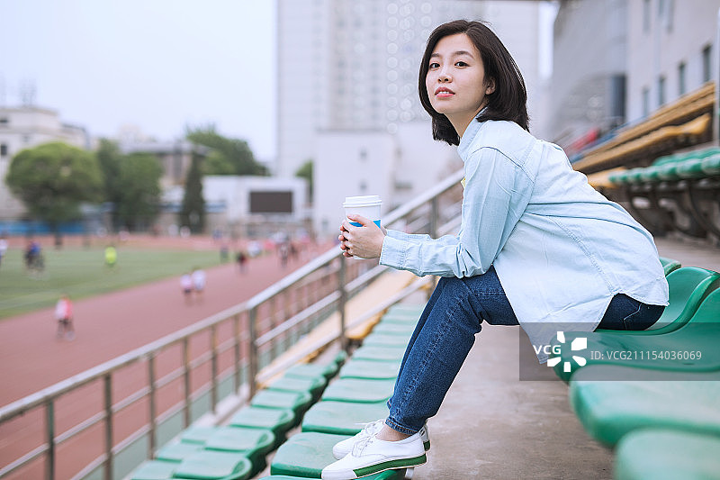 在学校看台观看球赛的女大学生图片素材