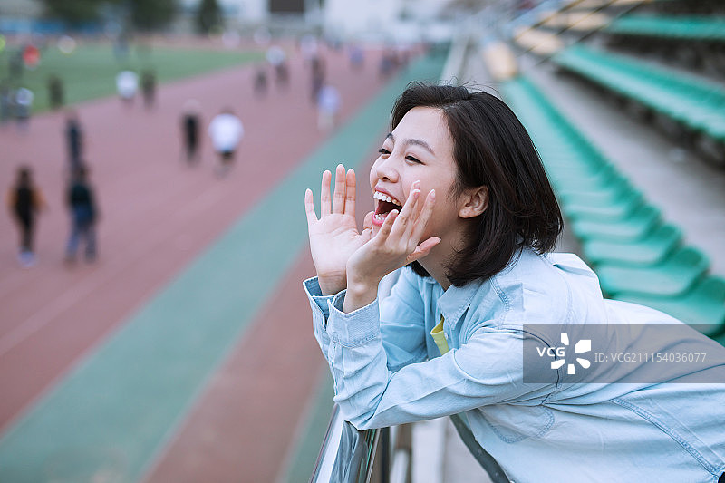 在学校看台观看球赛的女大学生图片素材