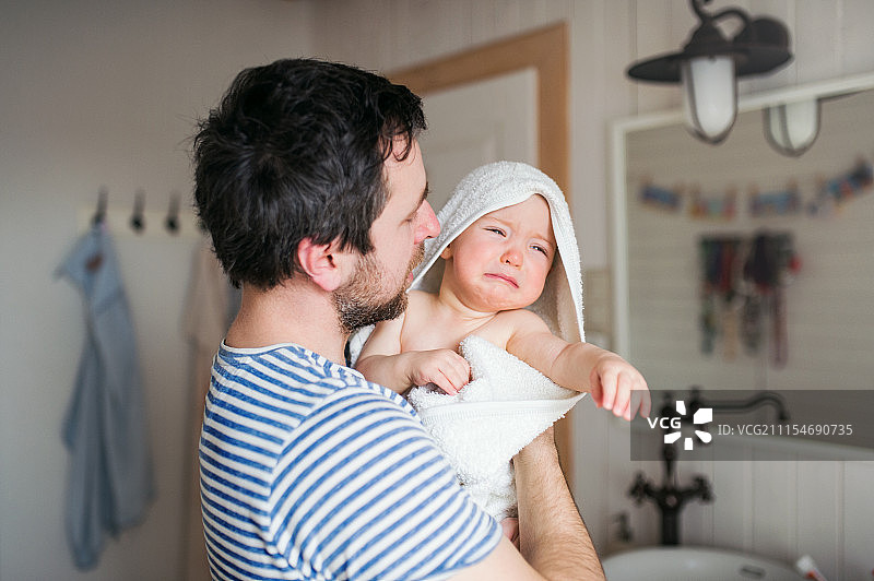父亲和裹着浴巾的幼儿在家中浴室图片素材