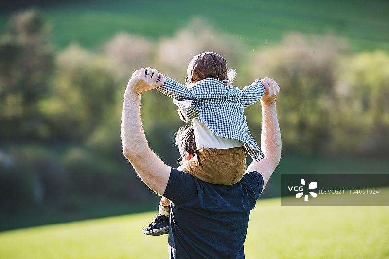 春天里，父亲背着蹒跚学步的儿子图片素材