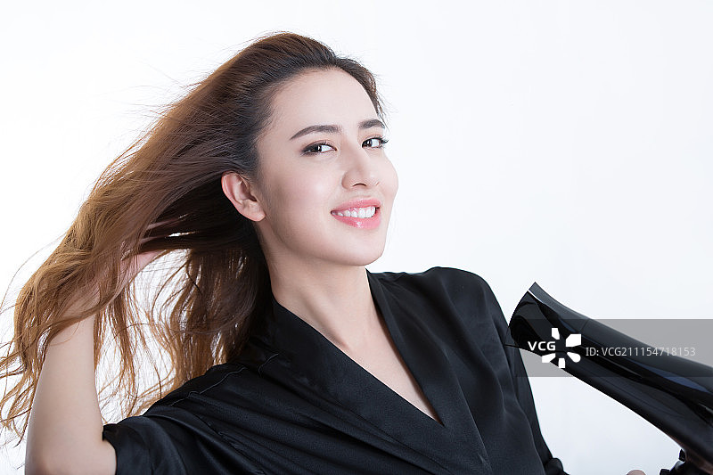 年轻女人用吹风机吹头发图片素材
