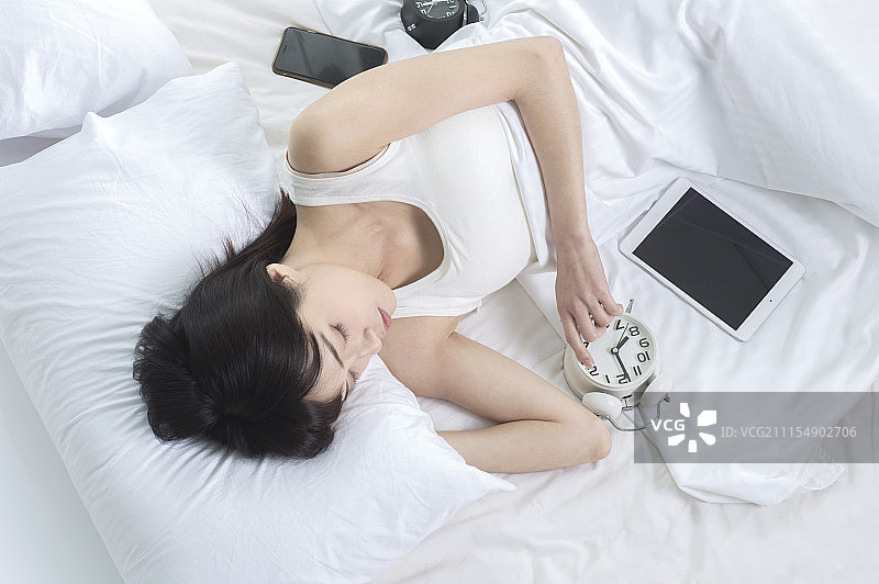 年轻女人躺在凌乱的床上睡觉图片素材