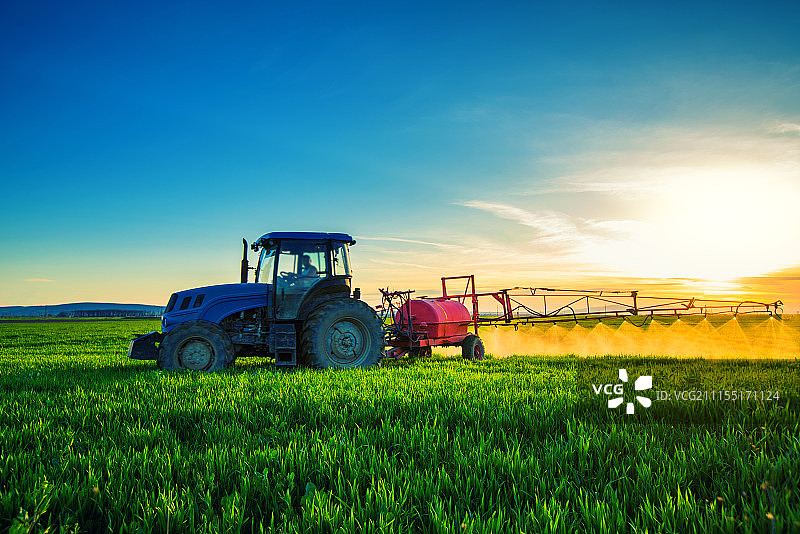 农业拖拉机在田间犁地和喷洒图片素材