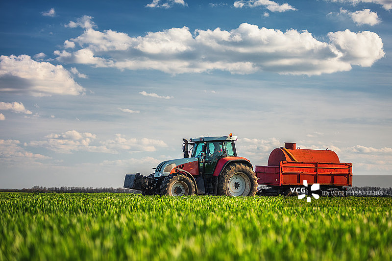 农业拖拉机在田间犁地和喷洒图片素材