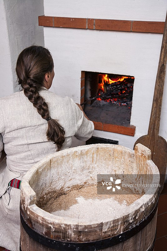 在爱沙尼亚 Hellenurme 水磨坊炉子旁的女人，木制揉捏槽图片素材