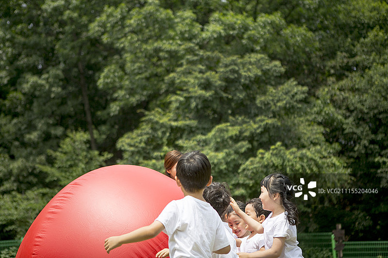 享受运动日滚红球的学龄前儿童摄影图片素材