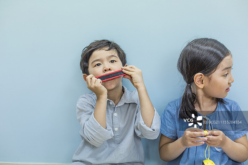 男孩与同学坐在一起吹口琴图片素材