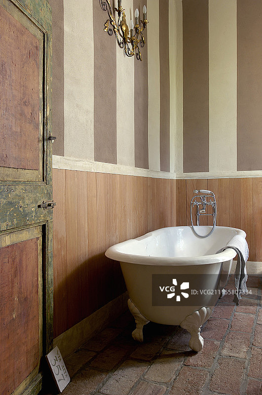 壁板条纹墙旁的独立式浴缸图片素材