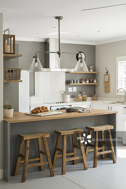 开放式改造厨房内带木制吧台凳的台面和灰色墙壁图片素材